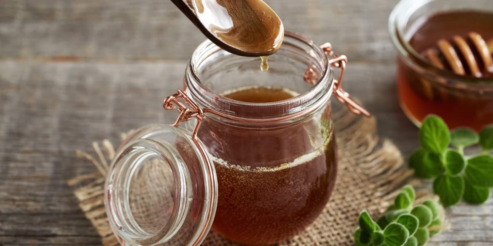 Homemade Plectranthus amboinicus syrup for common cold on a spoon above a glass jar